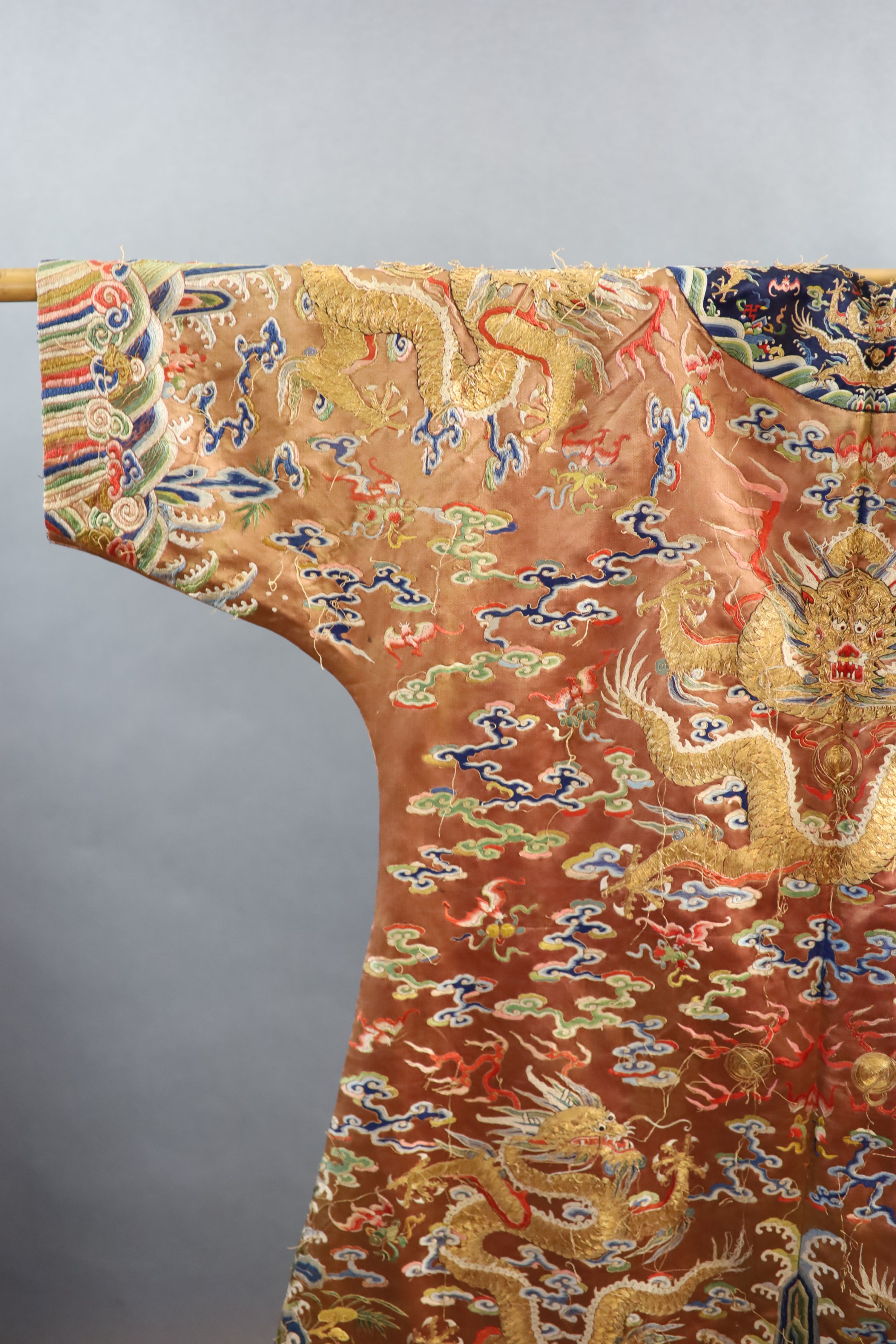 A Chinese apricot embroidered silk ‘dragon’ formal court robe, jifu, late Qing Dynasty, 131cm long, some alterations